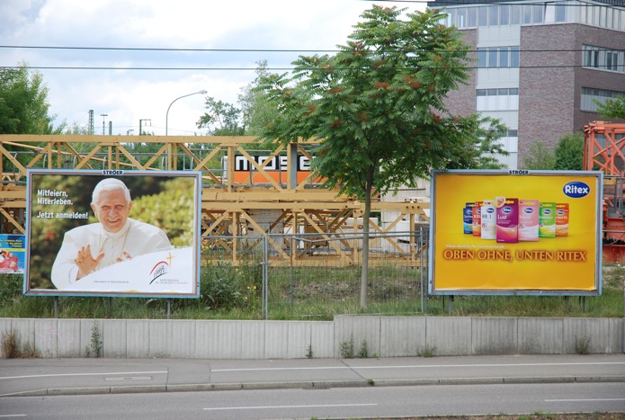 links Werbung für den Papstbesuch, rechts Ritex-Werbung